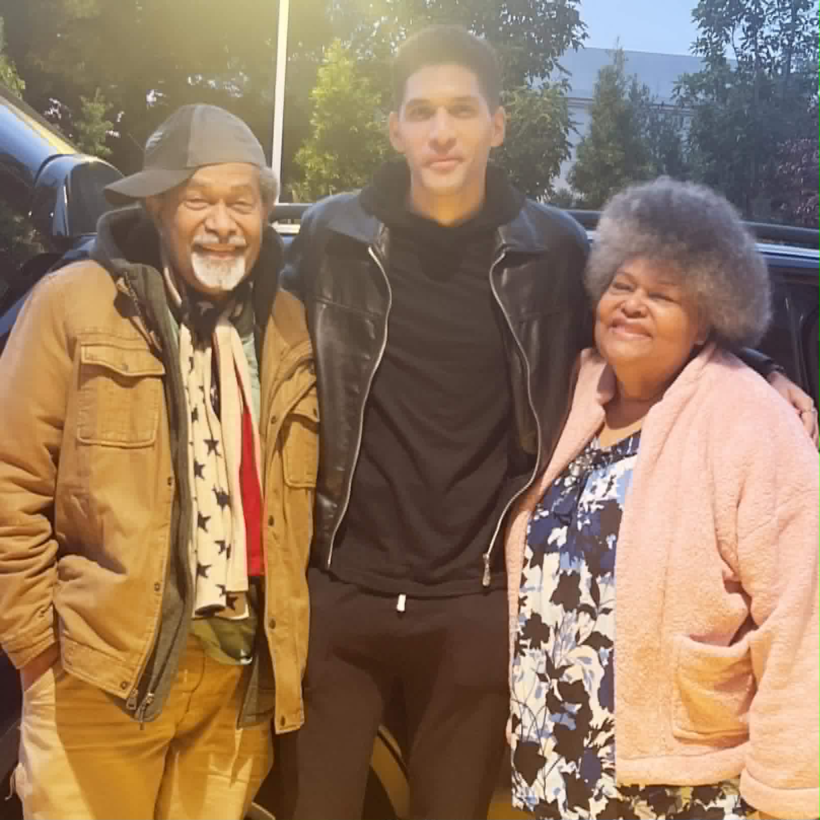 Three generations of family standing together outside, smiling warmly